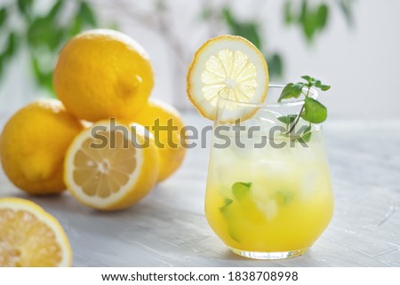 Citrus iced lemonade in the glass with lemon slice and mint leaves decoration on marble table on natural background. Fresh summer drink beautiful picture. Copy space