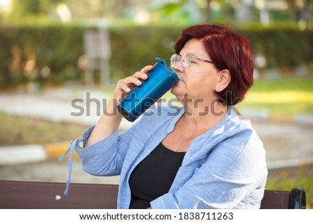 Senior woman with coffee in park