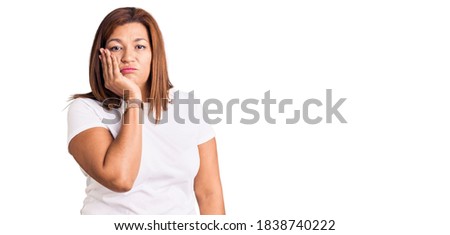 Middle age latin woman wearing casual white tshirt thinking looking tired and bored with depression problems with crossed arms. 