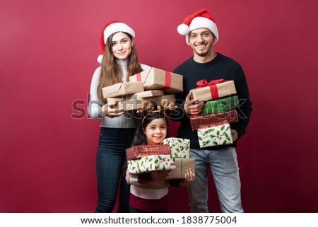 Cheerful Latin family carrying a lot of Christmas presents and getting ready to deliver them on a studio