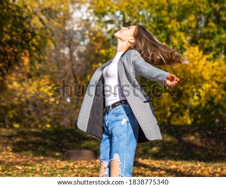 portrait of a young beautiful girl in stylish ripped jeans posing in an autumn park