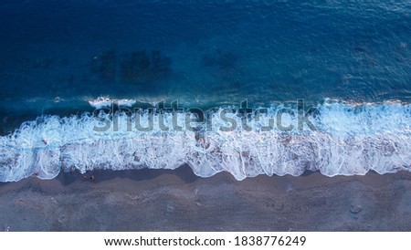 Aerial of a sea shoreline with cleaned up beach and people swimming in the stone cut entrance