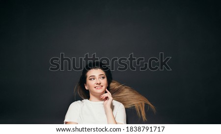 beautiful young woman with long hair lying on black studio background, happy student girl top view,concept success
