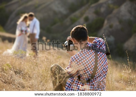 wedding professional photographer takes pictures of the bride and groom in nature in sunny day, man photographer in action