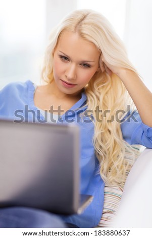 home, technology and internet concept - woman sitting on the couch with laptop computer at home
