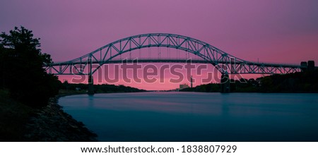Sagamore Bridge on Cape Cod Canal. Twilight Nightscape Silhouette Image with Pink and Turquoise Colors. Cross-processed Panoramic Image.
