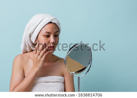 Beautiful Asian young woman touching face and was a feeling of anxiety on her face while looking at the mirror. Skincare and clean concept, Beauty treatment process for rejuvenation. Royalty-Free Stock Photo #1838814706