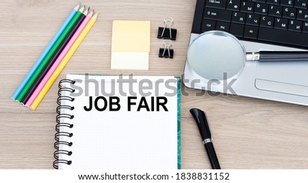 White notepad and pen on the wooden desk Job Fair Concept next to laptop.