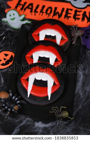 Vampire fangs protruding from scarlet lips, Glazed honey gingerbread cookies. Halloween food idea