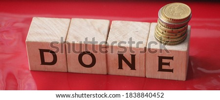 wooden cubes with message "done" on red background and coins. Business idea concept.