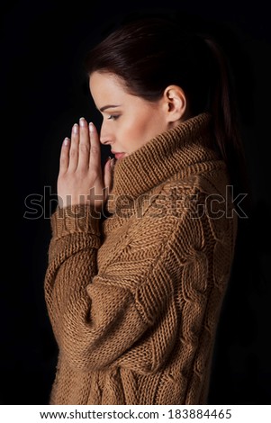 Young woman praying. Over black background.