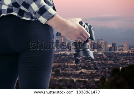 Female photographer or tourist hiking solo as a social distance activity outdoors with a camera and taking a photo of the Los Angeles cityscape