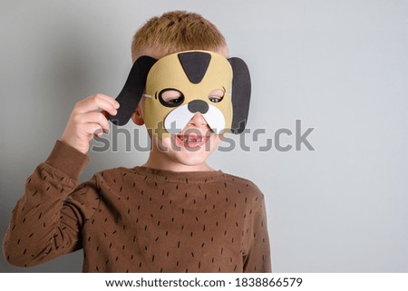 portrait of a boy smiling without a tooth in a dog mask. isolated on gray background