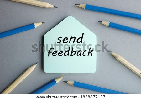 Send Feedback, text on blue paper on a gray background near blue and beige pencils.