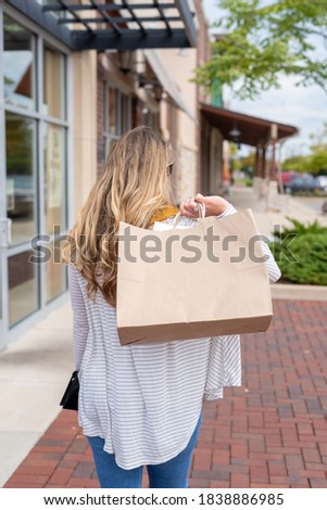Backview of young woman walking down the sidewalk carrying shopping bags