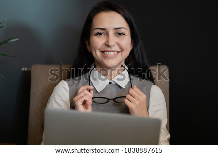 a businesslike young woman looks at the camera and smiles sincerely, holding computer glasses in her hands. working on the project task strategy to increase sales in a new company