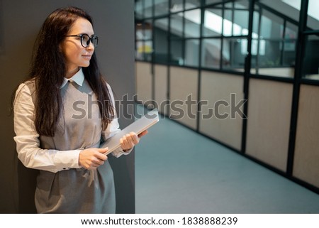 holds a laptop in his hands, statistics report in online form on traffic sales of a new site service in a large company. A brunette young woman of Caucasian appearance looks away
