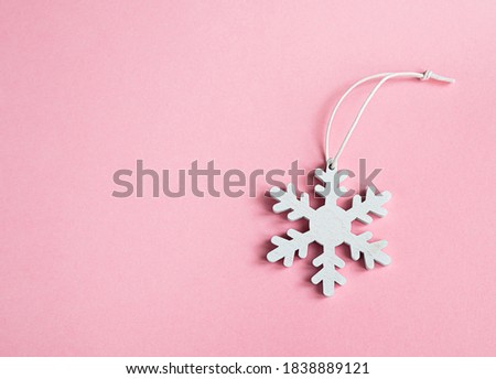 White snowflake on a pink background. Concept of Christmas, New Year, winter in minimal style, flat lay