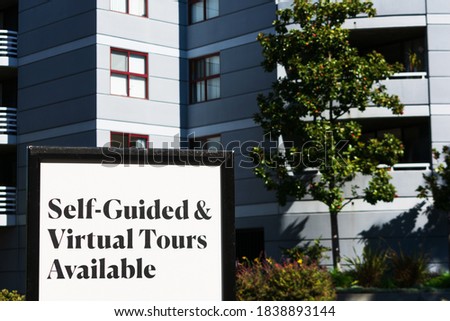 Self-Guided and Virtual Tours Available sign near a luxury apartment building.