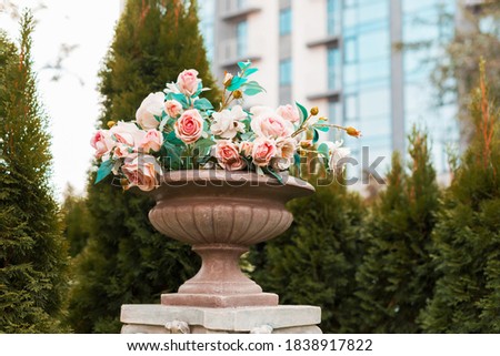 A picture of some beautiful baby pink roses in a stone vase outside
