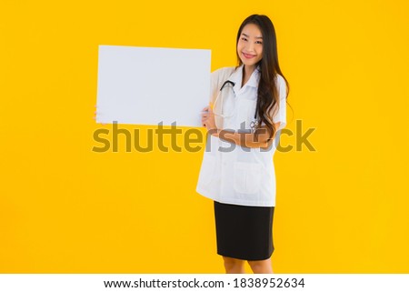 Portrait beautiful young asian doctor woman with empty white board on yellow isolated background