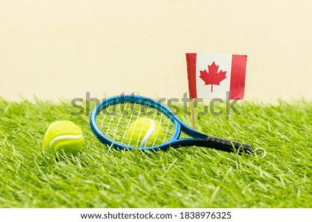 Tennis ball with flag of Canada are on green grass