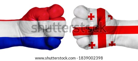 The concept of the struggle of peoples. Two hands are clenched into fists and are located opposite each other. Hands painted in the colors of the flags of the countries. France vs Georgia