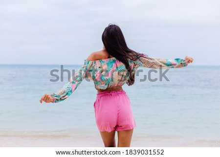 Happy woman with long hair in pink shorts enjoy time on beach by sea 