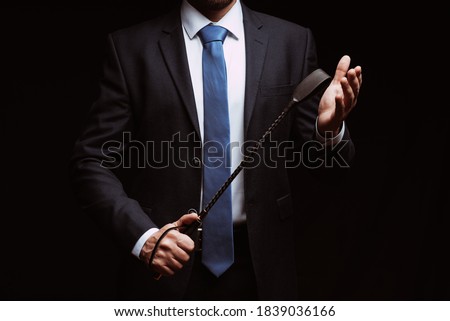 male dominant holds a leather whip Flogger  Royalty-Free Stock Photo #1839036166