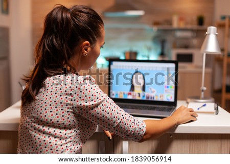 Creative freelancer retouching images in home office on notebook during night time. Photographer doing post production using software and performance laptop, artist, occupation, screen, graphic