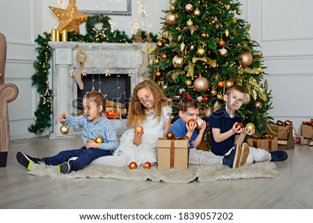 A group of children under a Christmas tree at home. Boys and girls in fancy costumes celebrate winter holidays. Children open gifts by the fireplace.