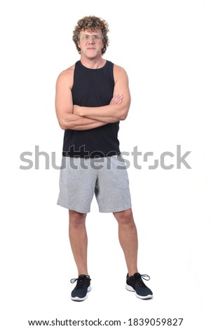 front view of a man wearing sportswear tank topsand shorts on white background, arms crossed