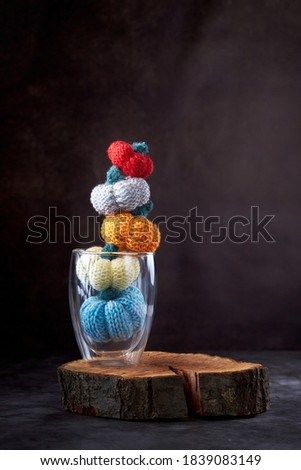 Five multi-colored knitted pumpkins in a glass
