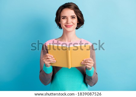 Photo portrait of cute female girl with short hair keeping yellow book smiling isolated on bright blue color background Royalty-Free Stock Photo #1839087526