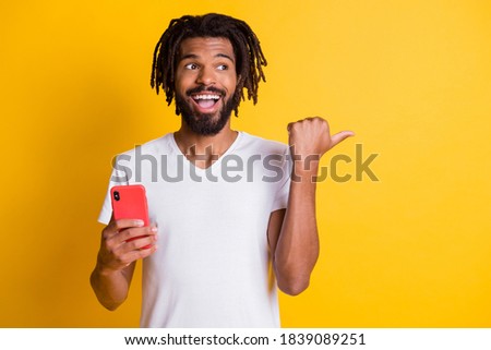Photo of interested dark skin guy hold telephone direct finger side empty space novelty isolated yellow color background