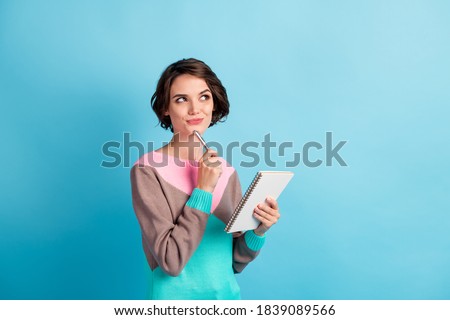 Photo portrait of curious girl thinking about idea keeping pen notebook looking at copyspace isolated on bright color blue background Royalty-Free Stock Photo #1839089566