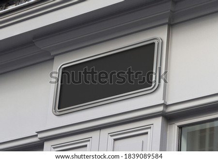 Black storefront on a grey shop frontage Mockup. Empty store brand signboard frame in street