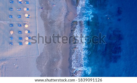 Aerial of a sea shoreline with cleaned up beach and people swimming in the stone cut entrance