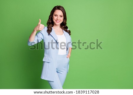 Photo of lovely woman curly hairstyle show thumb up hand pocket wear blue blazer isolated green color background