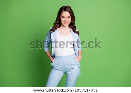 Photo of lovely woman curly hairstyle hands pockets wear blue jacket pants isolated green color background