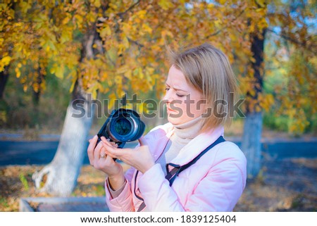 A young girl photographer walks through the forest and takes pictures of nature on a dslr camera. gold autumn
