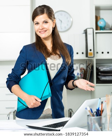 Young female office worker is standing with documents before signing it in office. High quality photo