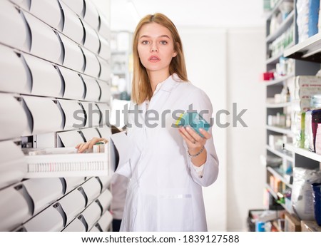 Young glad female customer searching for reliable drug in pharmacy. High quality photo