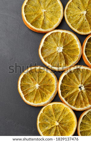 Dried orange slices on dark stony background.