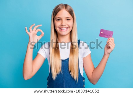 Portrait of positive nice blond hair girl hold bank card show ok sign buy for sale isolated on pastel blue color background