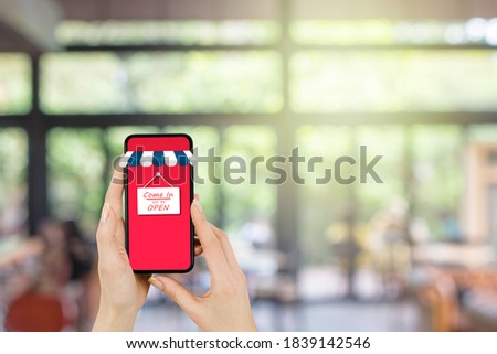 Open text wording label on smartphone screen with cafe shop or restaurant in background.