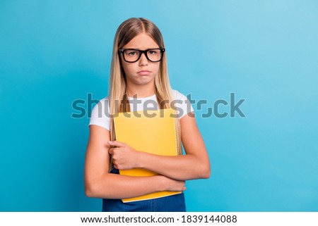 Photo of sad pupil girl do not want do homework wear spectacles hold book isolated on pastel blue color background