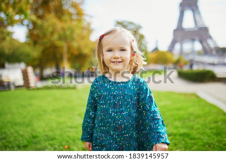 Adorable toddler girl walking near the Eiffel tower in Paris, France. Happy child enjoying fall day. Outdoor autumn activities for kids