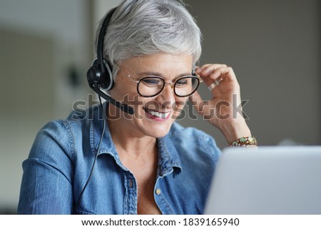 Mature woman with grey short hair working from home during pandemia