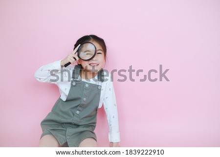 Portrait beautiful cute asian child girl on pink background playing magnifying glass Royalty-Free Stock Photo #1839222910